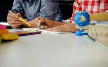 Education concept. Students studying and brainstorming campus concept. Close up of students discussing their subject on books textbooks and writing to notebook. Seclective focus.